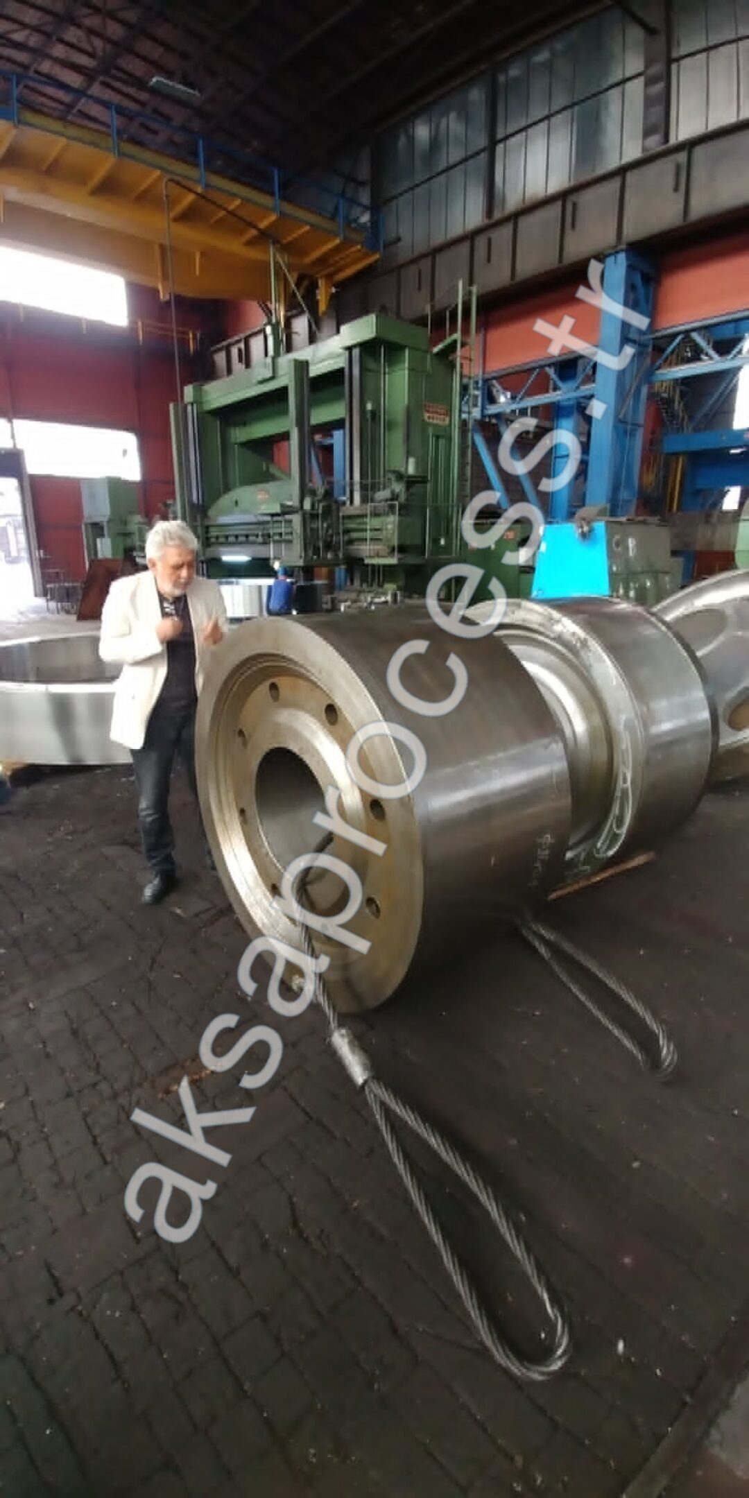 Our founder beside a large machined mill roller with lifting slings on the workshop floor